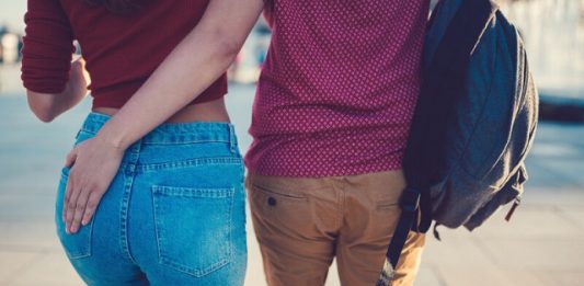 Un bărbat cu mâna stângă pe fundul unei tinere