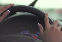 Mâinile unei femei pe volanul unui autoturism