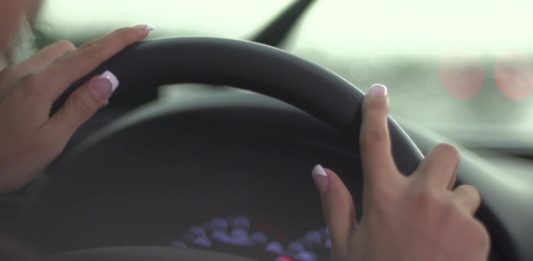 Mâinile unei femei pe volanul unui autoturism