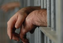 Mainile unui barbat pe gratiile unui penitenciar