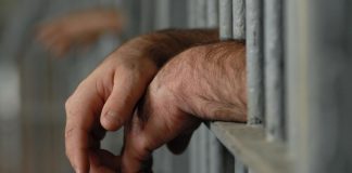 Poliţist, condamnat de judecătorii ieşeni după o dispută cu un deţinut! Agentul a spus că individul ar fi fost recalcitrant! (EXCLUSIV) Mainile unui barbat pe gratiile unui penitenciar